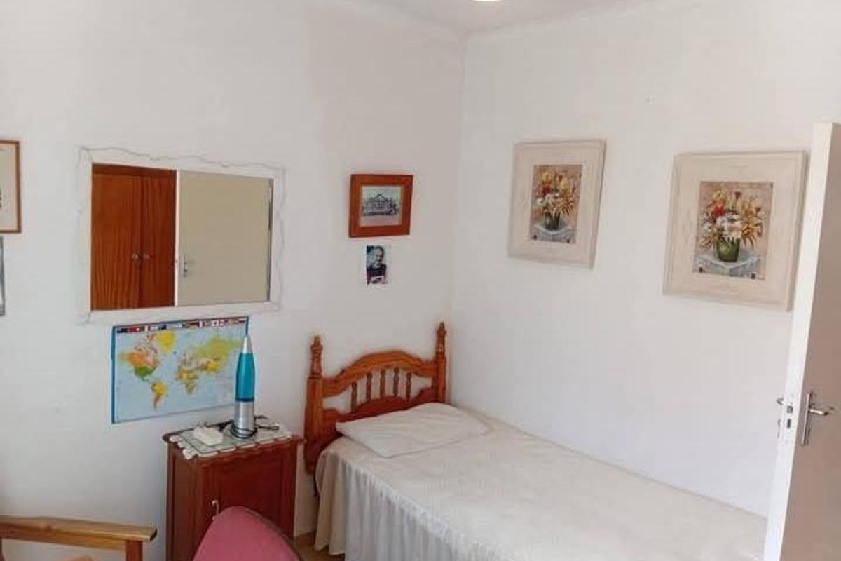 A compact bedroom featuring neutral walls and a built-in cupboard, offering a functional space for a single bed.