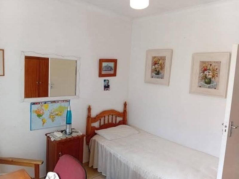 A compact bedroom featuring neutral walls and a built-in cupboard, offering a functional space for a single bed.