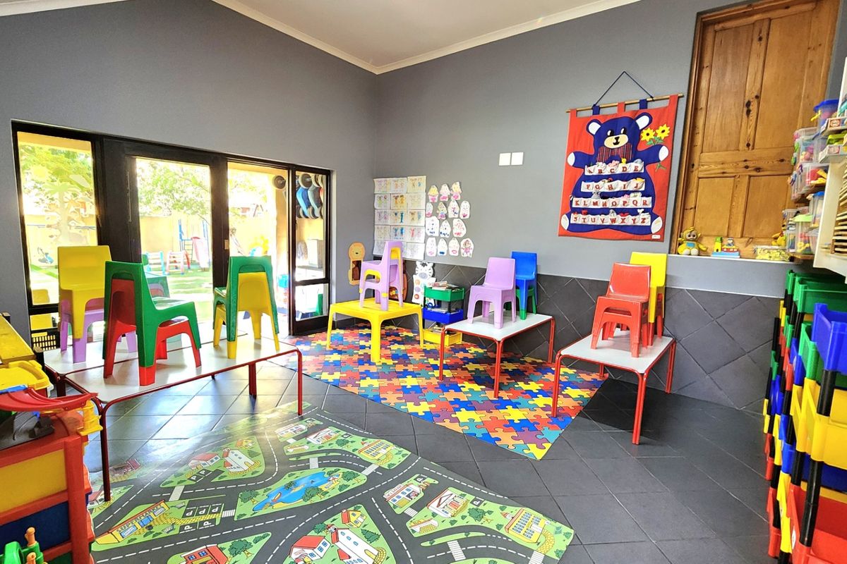 A multi-purpose room featuring tiled flooring and sliding glass doors providing access to the outdoor area, currently utilized as a play space.