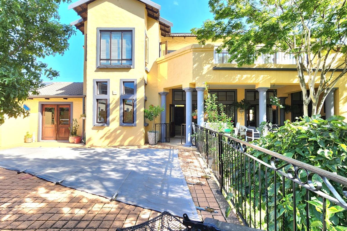 Rear view of the property featuring a covered patio, swimming pool with cover, paved terrace, and a balcony overlooking the garden area.