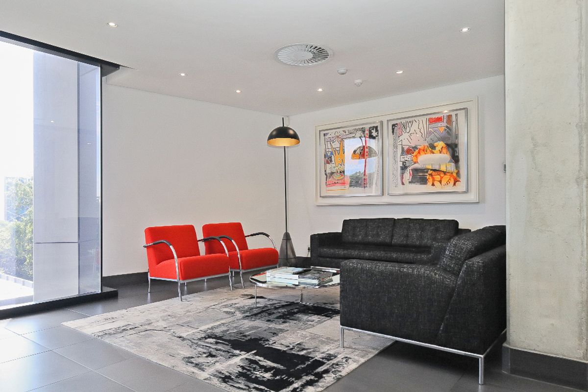 A modern commercial lounge area featuring tiled flooring, a prominent concrete column, and large windows providing natural light.
