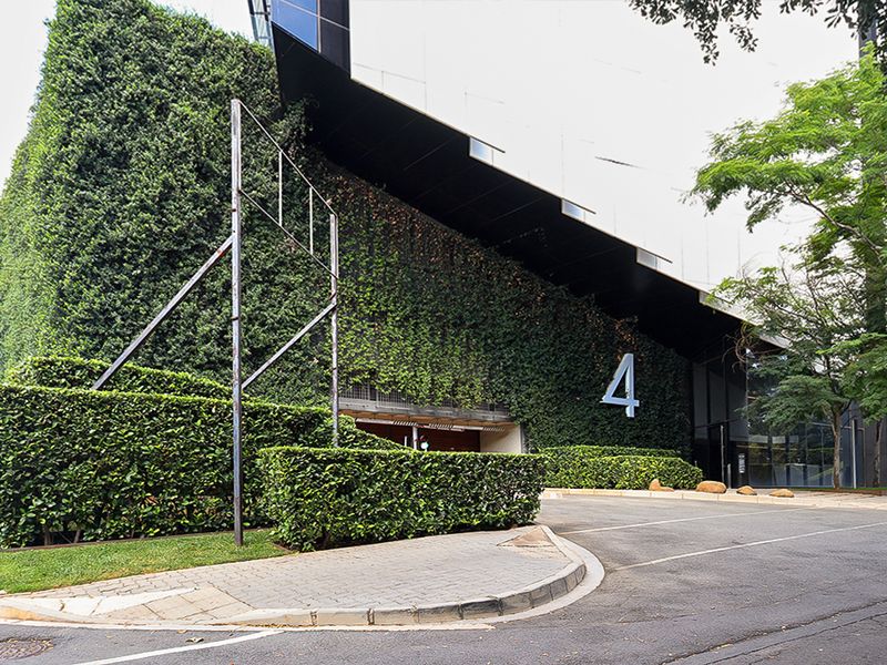 Modern commercial building exterior featuring a prominent vertical garden, paved driveway, and glass facade with clear street-level signage.