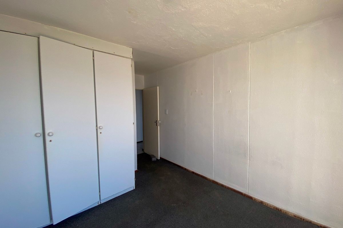 An empty bedroom featuring built-in cupboards, carpeted flooring, and a neutral color palette, ready for personalization.