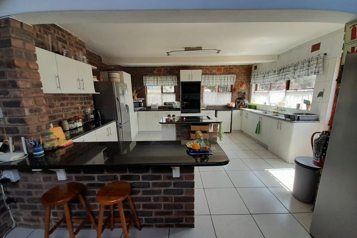 Spacious kitchen featuring exposed brick walls, ample built-in cabinetry, granite countertops, a central island, and a built-in oven.