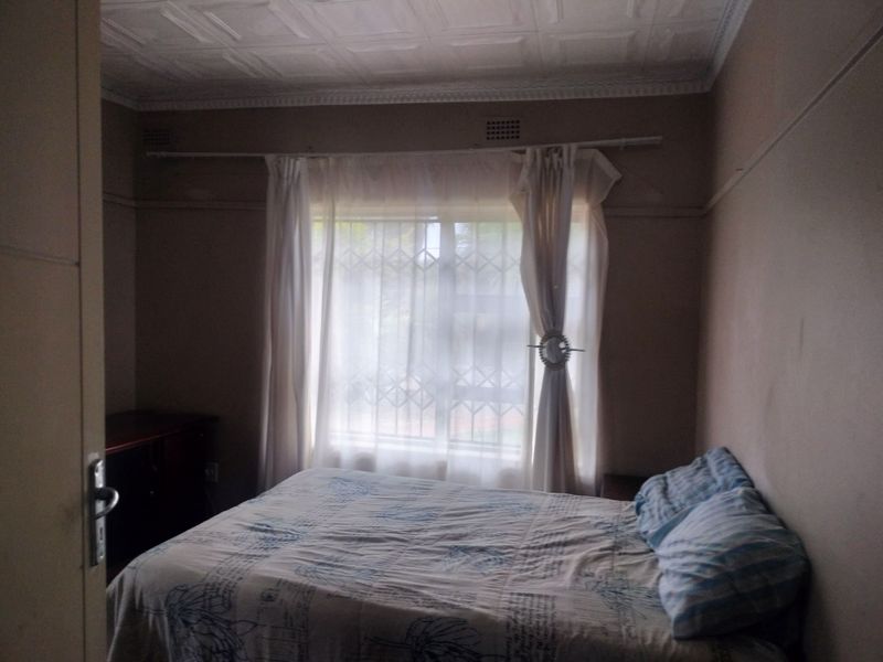 A bedroom featuring a classic pressed metal ceiling, picture rails, and a window fitted with a security gate.
