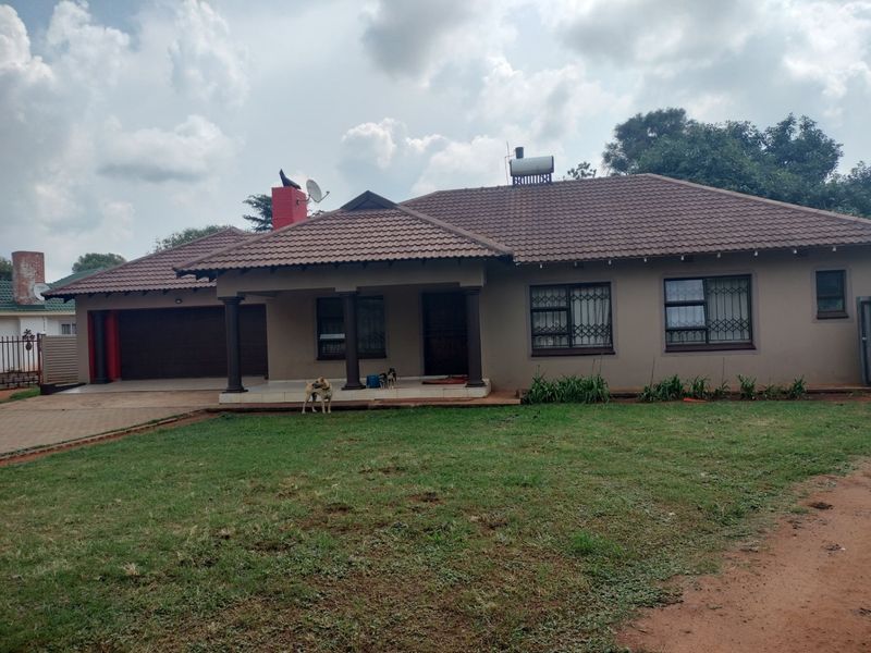 A well-maintained single-story residential home featuring a tiled roof, solar water heating system, integrated garage, and a covered front porch.
