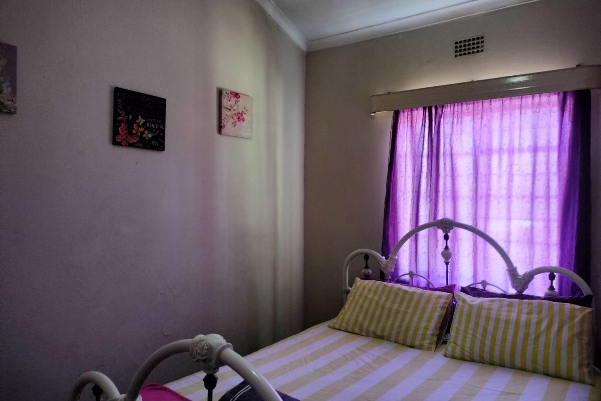 A standard bedroom featuring a window with a curtain rail and a wall-mounted ventilation grille.