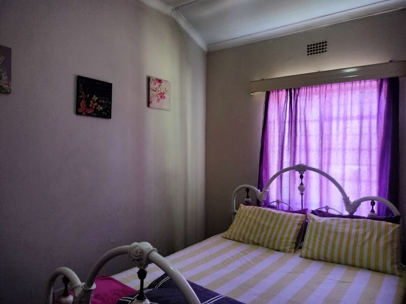 A standard bedroom featuring a window with a curtain rail and a wall-mounted ventilation grille.