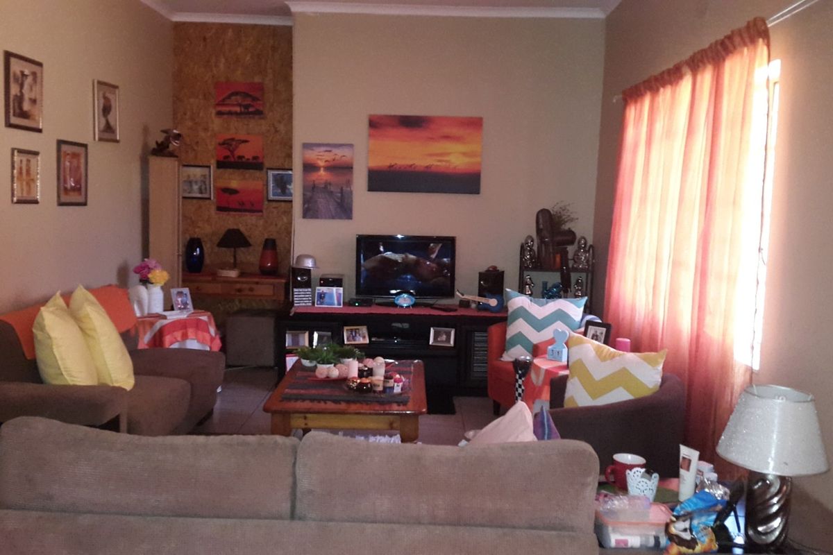 A comfortable living room space featuring tiled flooring and natural light through a window with curtains.