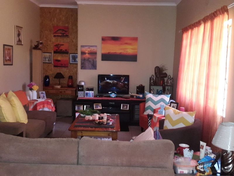 A comfortable living room space featuring tiled flooring and natural light through a window with curtains.