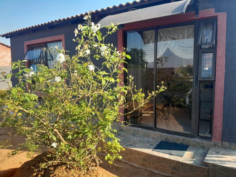 Rear exterior view of the property featuring a tiled patio area, sliding glass doors, and a protective awning over the entrance.