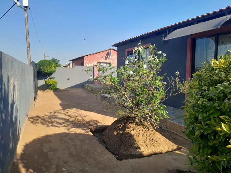 Rear exterior area featuring a paved courtyard, perimeter wall, and direct access to the home via a sliding door.