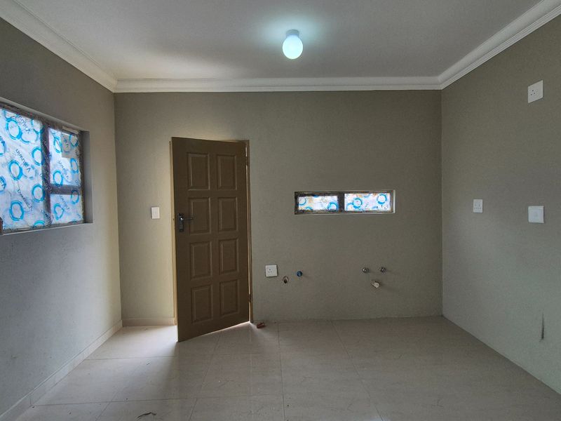 A clean, empty utility or laundry room featuring tiled flooring, plumbing connections for appliances, and neutral wall finishes.