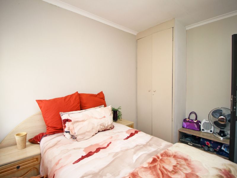 A functional bedroom featuring a built-in wardrobe and neutral wall finishes, providing a practical space for rest.