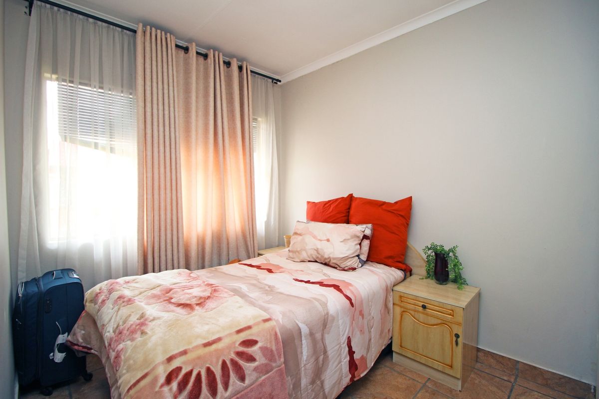 A functional bedroom featuring tiled flooring and natural light through window treatments.