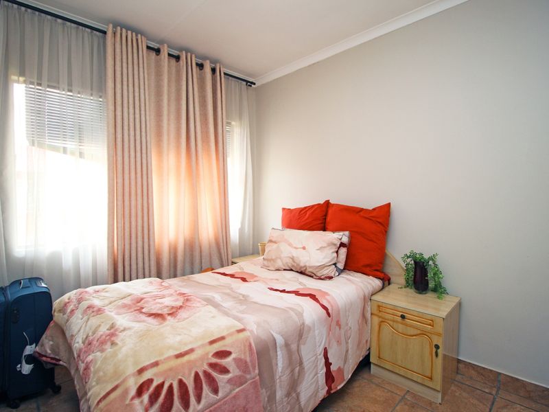 A functional bedroom featuring tiled flooring and natural light through window treatments.