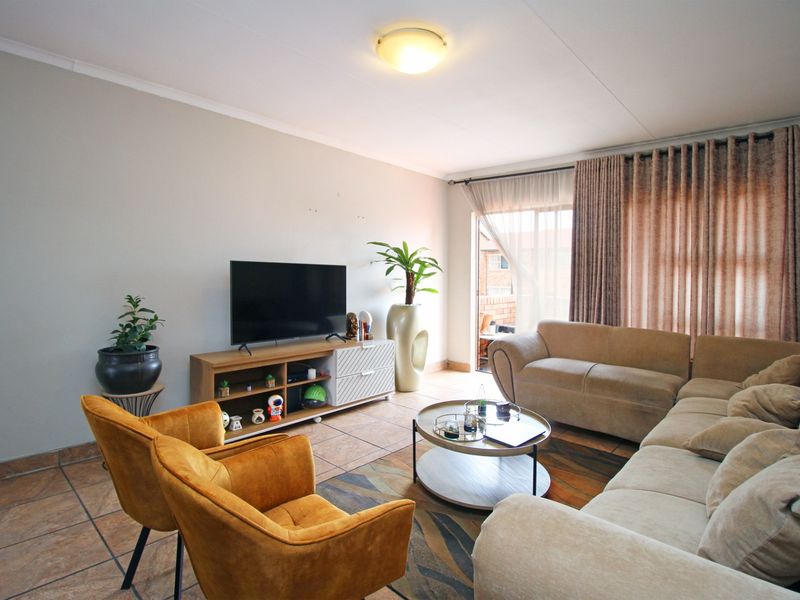 A comfortable living room featuring tiled flooring, neutral walls, and a sliding glass door providing access to an outdoor area.