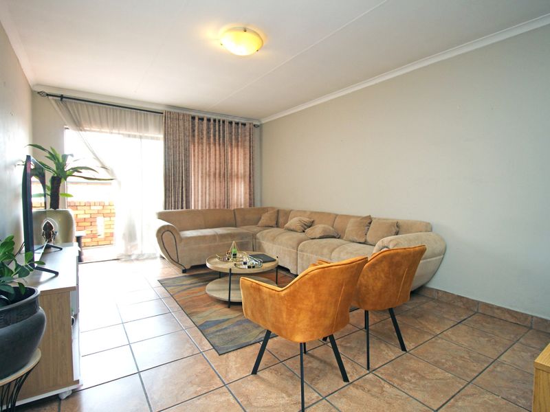 A well-lit living room featuring tiled flooring and a sliding glass door providing access to an outdoor area.