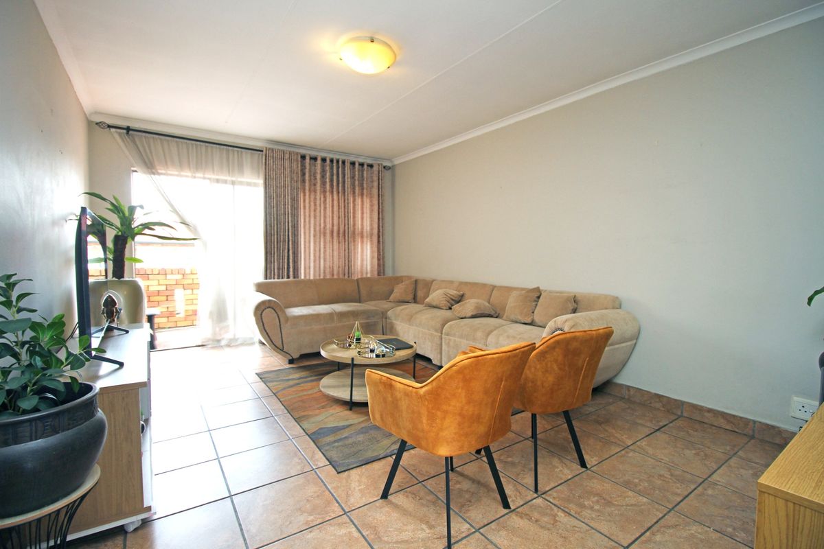 A well-lit living room featuring tiled flooring and a sliding glass door providing access to an outdoor area.