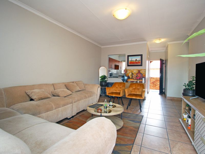 Open plan living area featuring tiled flooring, neutral walls, and a convenient pass-through window connecting to the kitchen space.