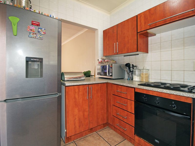 A functional kitchen featuring wood-look cabinetry, granite-style countertops, built-in oven, electric hob, and tiled splashbacks.