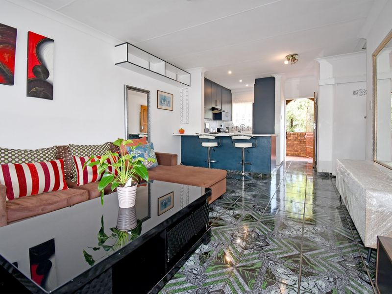 Open-plan living area featuring a kitchen with breakfast bar and distinctive tiled flooring, creating a functional and connected space.