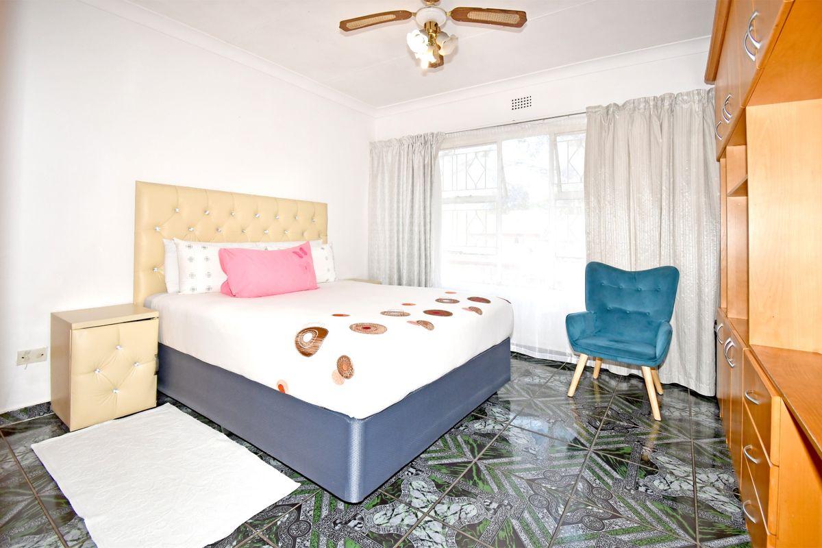 A bedroom featuring tiled flooring, a ceiling fan, and built-in cabinetry, offering a functional space with natural light.