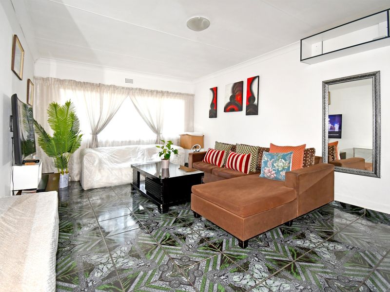 A living room featuring patterned tiled flooring and neutral walls, providing a functional space for relaxation.