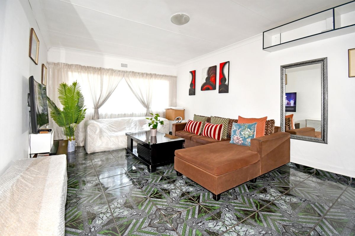 A living room featuring patterned tiled flooring and neutral walls, providing a functional space for relaxation.