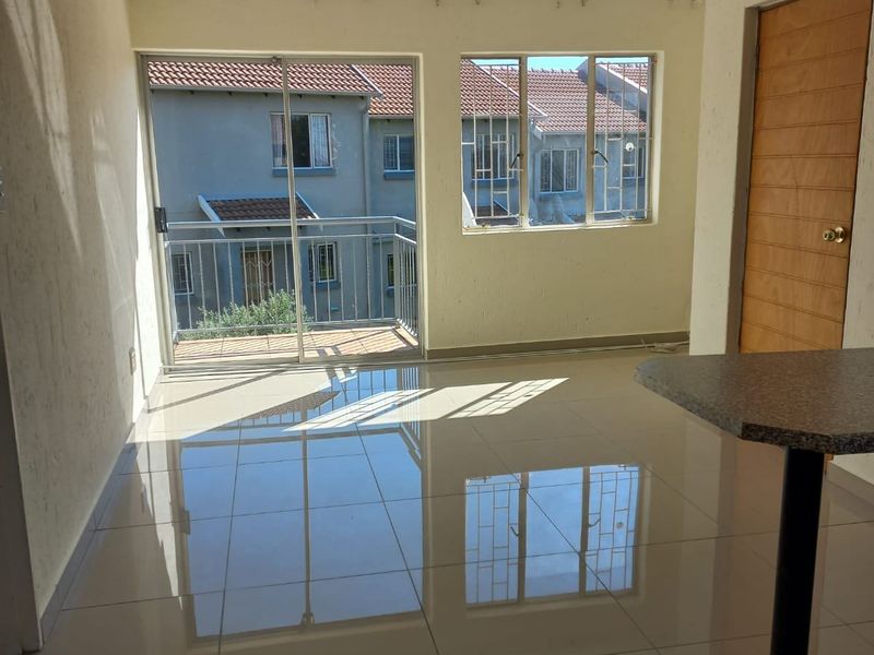 Bright open plan living area featuring large sliding glass doors leading to a balcony, tiled flooring, and a breakfast counter.