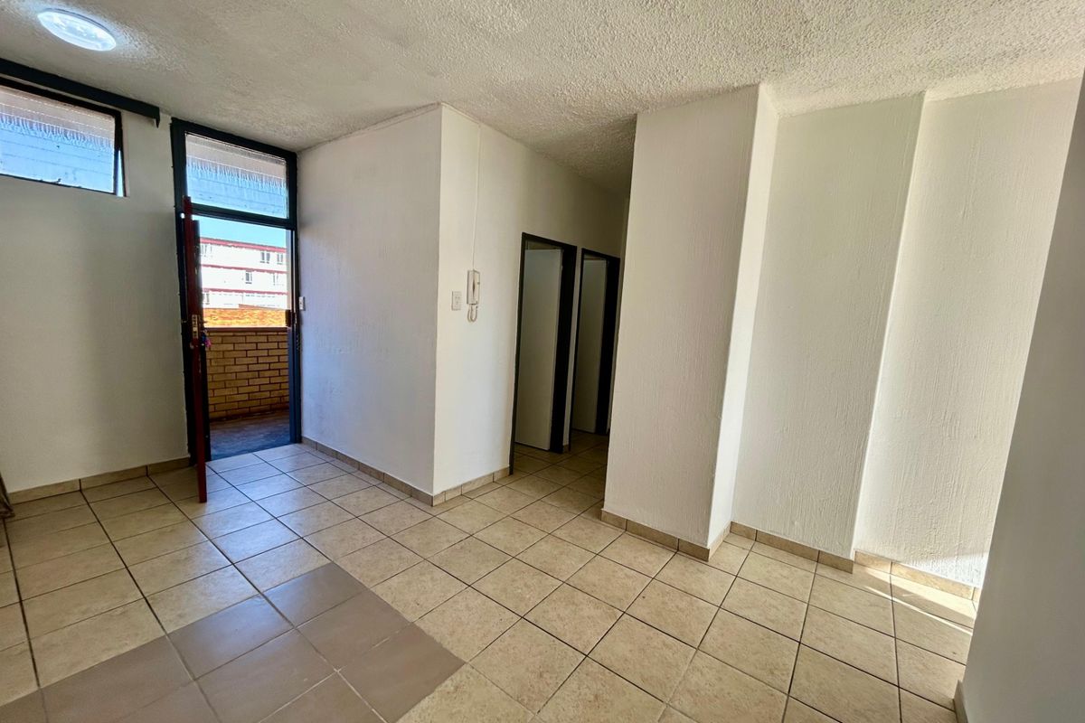 An empty living area featuring tiled flooring, an intercom system, and direct access to an outdoor balcony space.