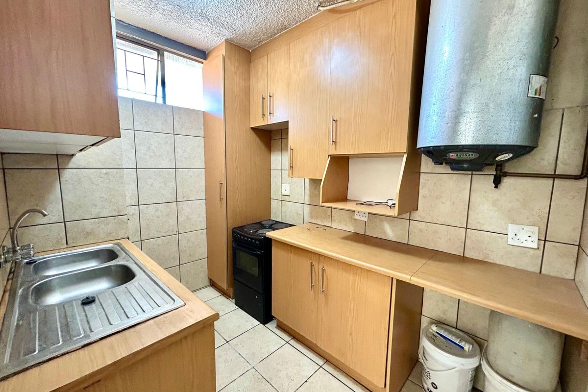 Compact kitchen featuring laminate cabinetry, tiled splashbacks, a double bowl stainless steel sink, and an integrated electric stove.