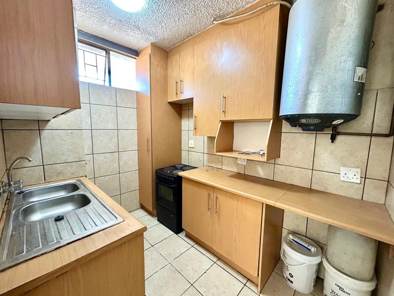 Compact kitchen featuring laminate cabinetry, tiled splashbacks, a double bowl stainless steel sink, and an integrated electric stove.