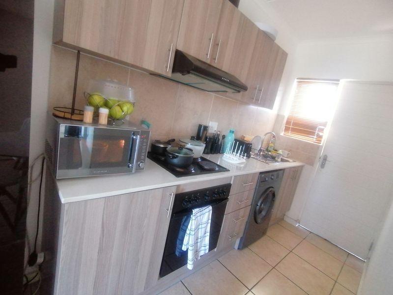 A functional kitchen featuring wood-look cabinetry, a built-in oven, hob, extractor fan, and integrated space for a washing machine.