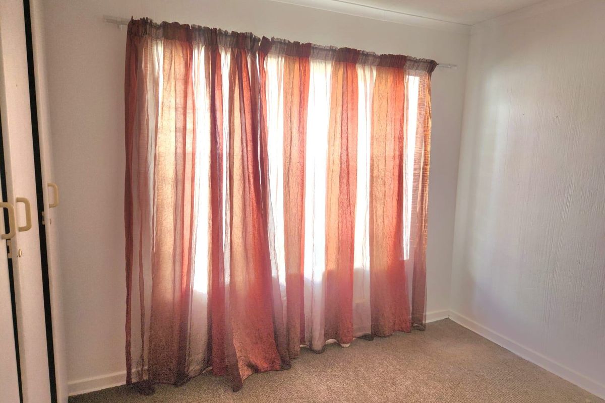 A vacant bedroom featuring neutral carpeted flooring and a built-in cupboard, offering a blank canvas for personalization.