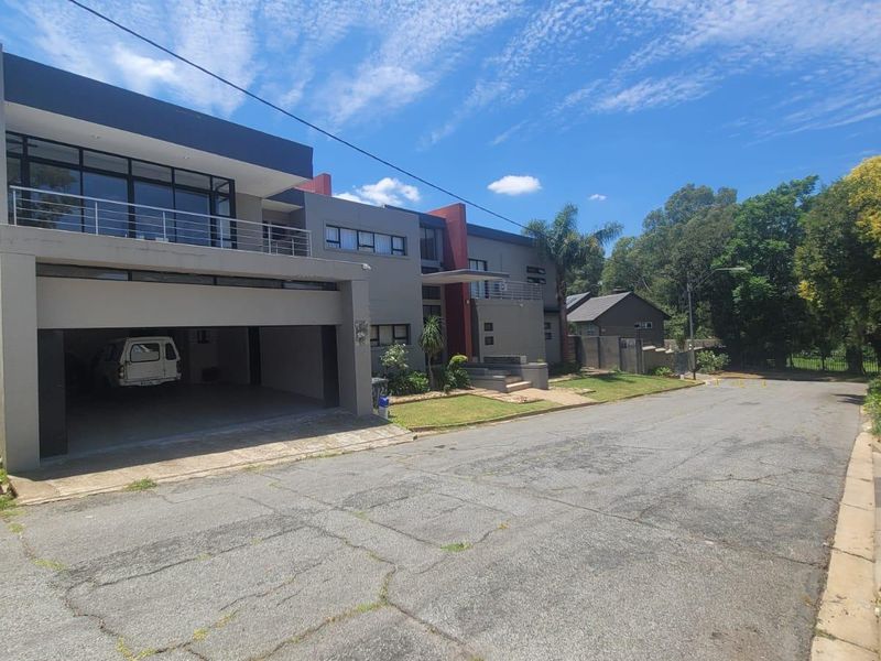 Modern multi-story residential property featuring a double garage, upper-level balcony with metal railings, and a paved driveway.
