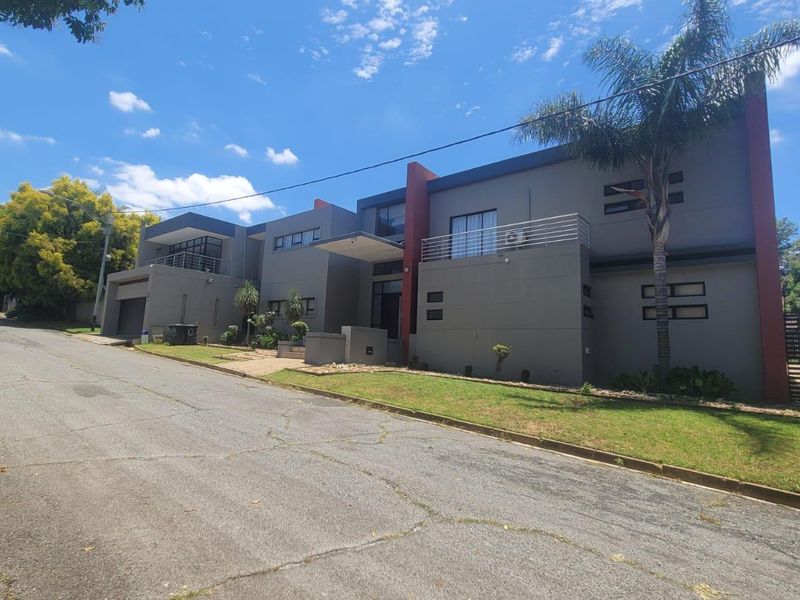 Modern double-storey residential property featuring a contemporary facade, integrated garage, and upper-level balconies, situated on a quiet street.
