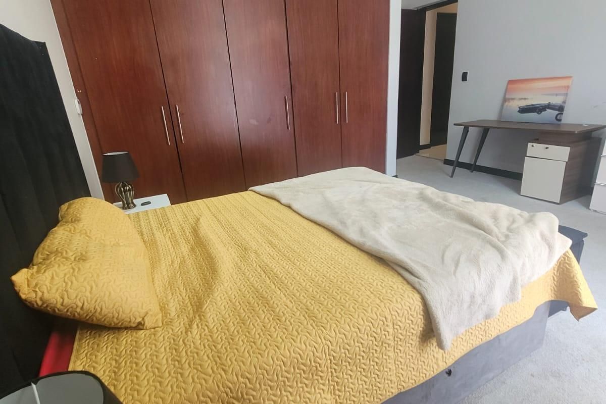 A bedroom featuring built-in wooden cupboards, carpeted flooring, and neutral wall finishes, providing a functional and well-proportioned sleeping space.