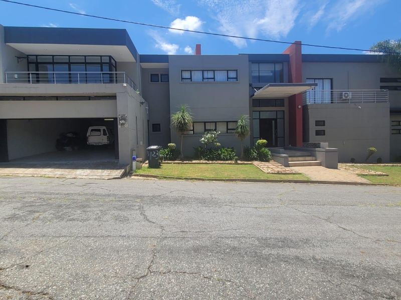 Modern double-story residential property featuring a contemporary facade, integrated double garage, upper-level balcony, and a well-maintained front garden.