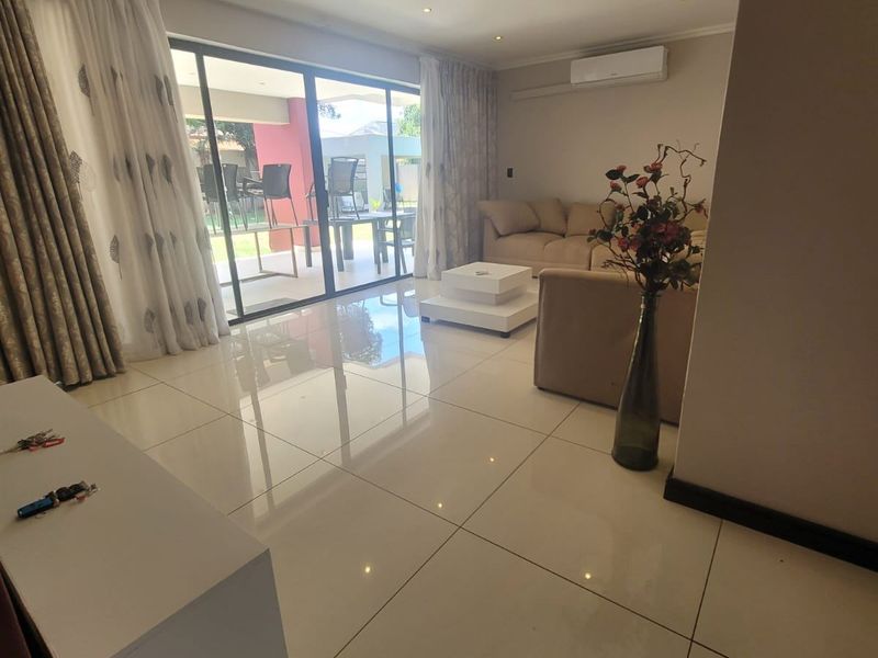 Spacious living room featuring large sliding glass doors leading to an outdoor patio, polished tiled flooring, and integrated recessed downlighting.