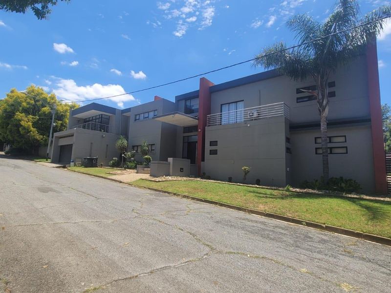 Modern double-storey residential property featuring a contemporary facade, integrated garage, and balcony, situated on a quiet street with established landscaping.