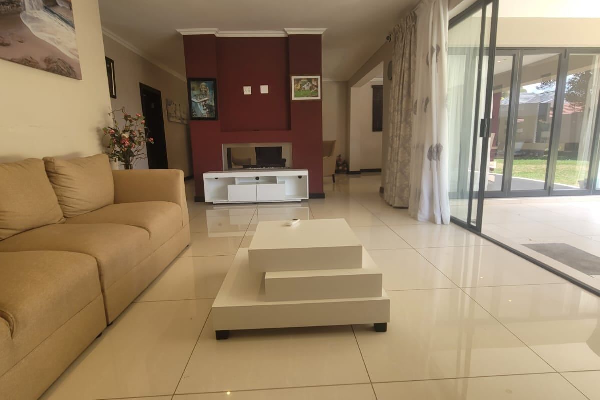 Spacious living room featuring large format floor tiles, a central built-in fireplace, and expansive sliding glass doors providing seamless access to the outdoor patio area.
