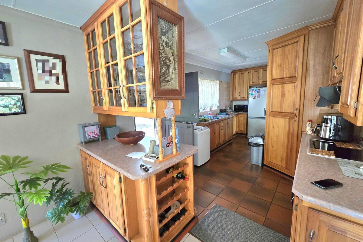 A functional kitchen featuring extensive wooden cabinetry, laminate countertops, a built-in wine rack, and tiled flooring with a classic layout.