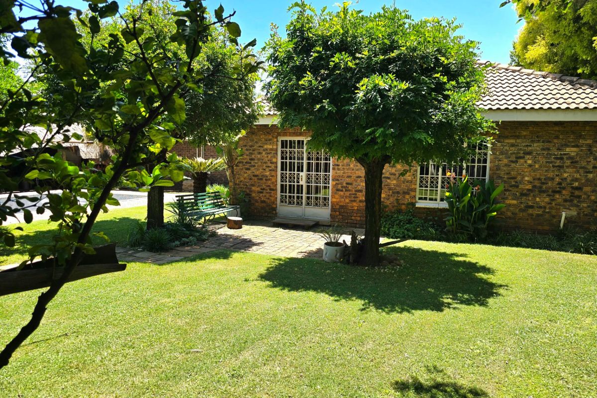 A well-maintained rear garden featuring a brick facade, paved patio area, and established trees, providing a pleasant outdoor space.