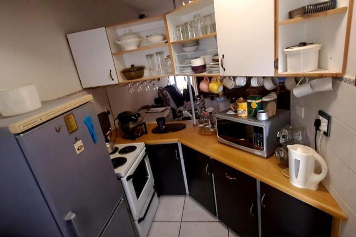 Compact kitchen featuring dark lower cabinetry, light upper shelving, tiled backsplash, and built-in stove, offering a functional layout for an apartment setting.