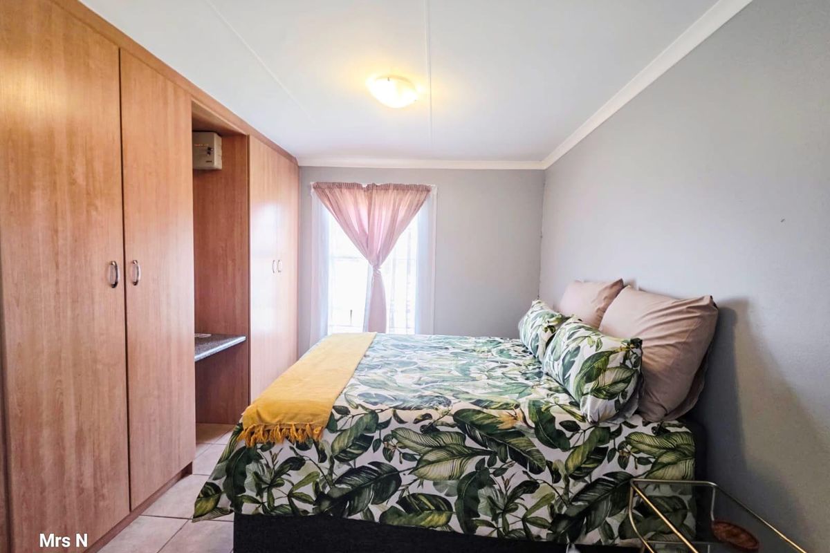 A bedroom featuring built-in wooden cupboards and tiled flooring, providing functional storage space and a neutral interior finish.