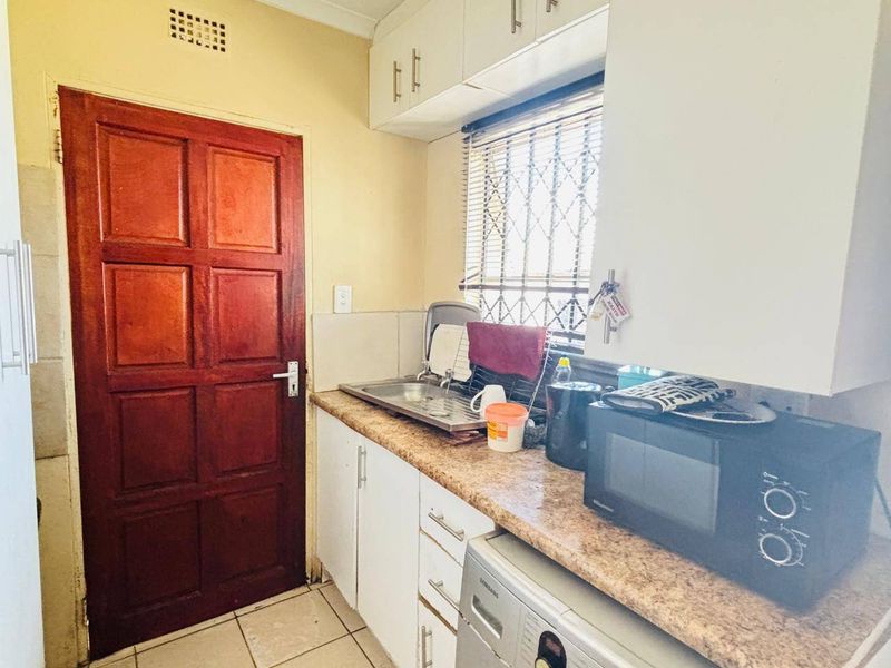 A functional scullery area featuring built-in cabinetry, a stainless steel sink, and tiled flooring, providing practical utility space for the home.