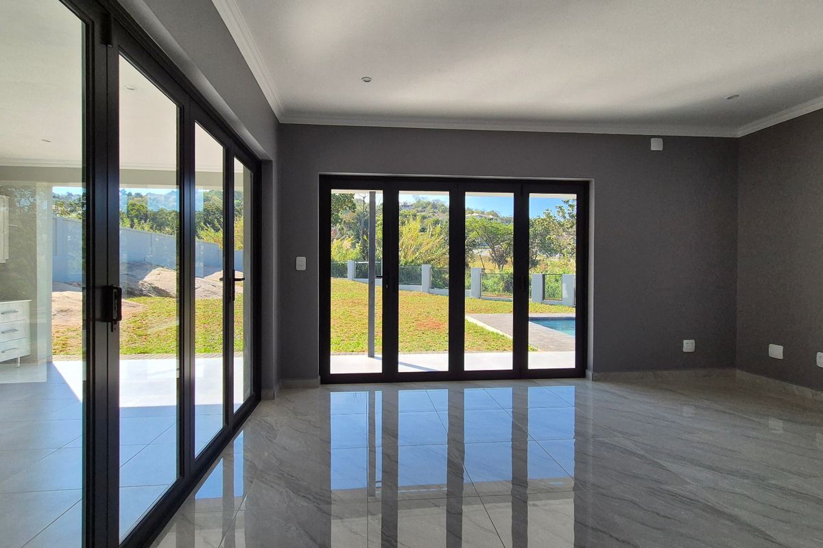 Spacious, modern living area featuring large format porcelain tiles, recessed lighting, and expansive aluminium stacker doors providing seamless access to the garden and pool area.