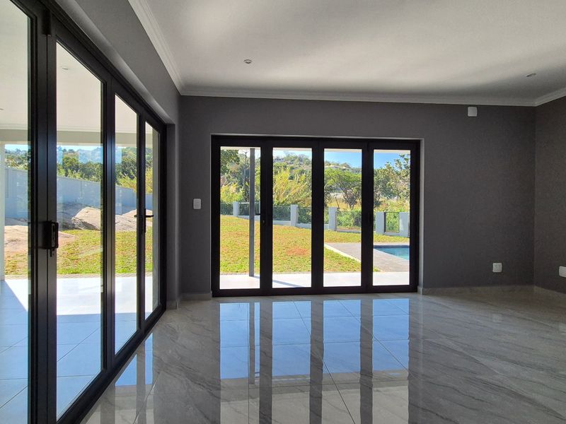 Spacious, modern living area featuring large format porcelain tiles, recessed lighting, and expansive aluminium stacker doors providing seamless access to the garden and pool area.