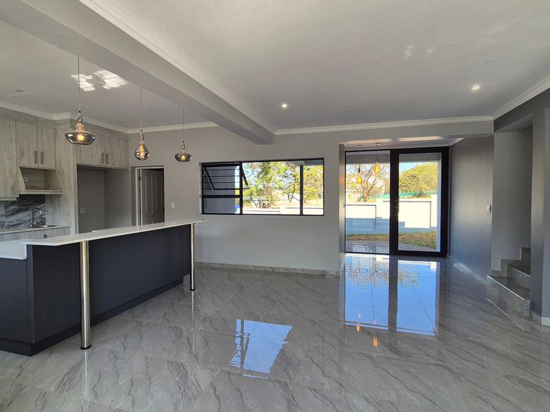 Modern open-plan living area featuring a sleek kitchen with island, high-gloss porcelain flooring, and seamless access to the outdoor space.